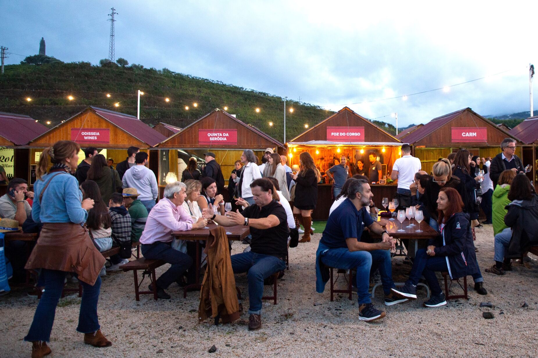 Foto de pessoas a comer e beber em festival de vinho na zona do Douro.